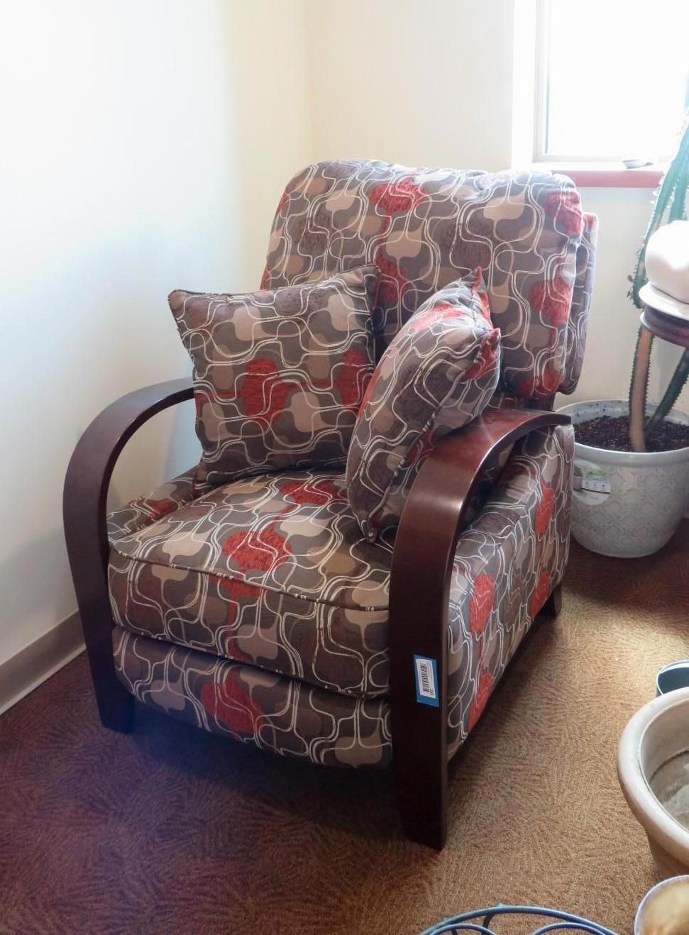 Upholstered armchair with brown floral pattern, dark wooden frame, and two matching pillows.