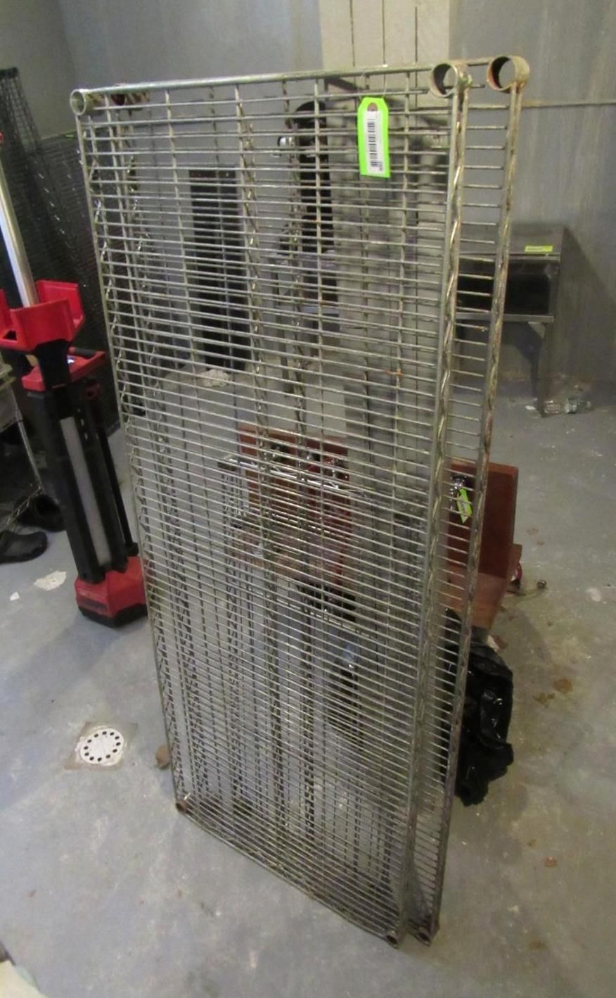 Tall, wire-mesh rack on a concrete floor in a room.