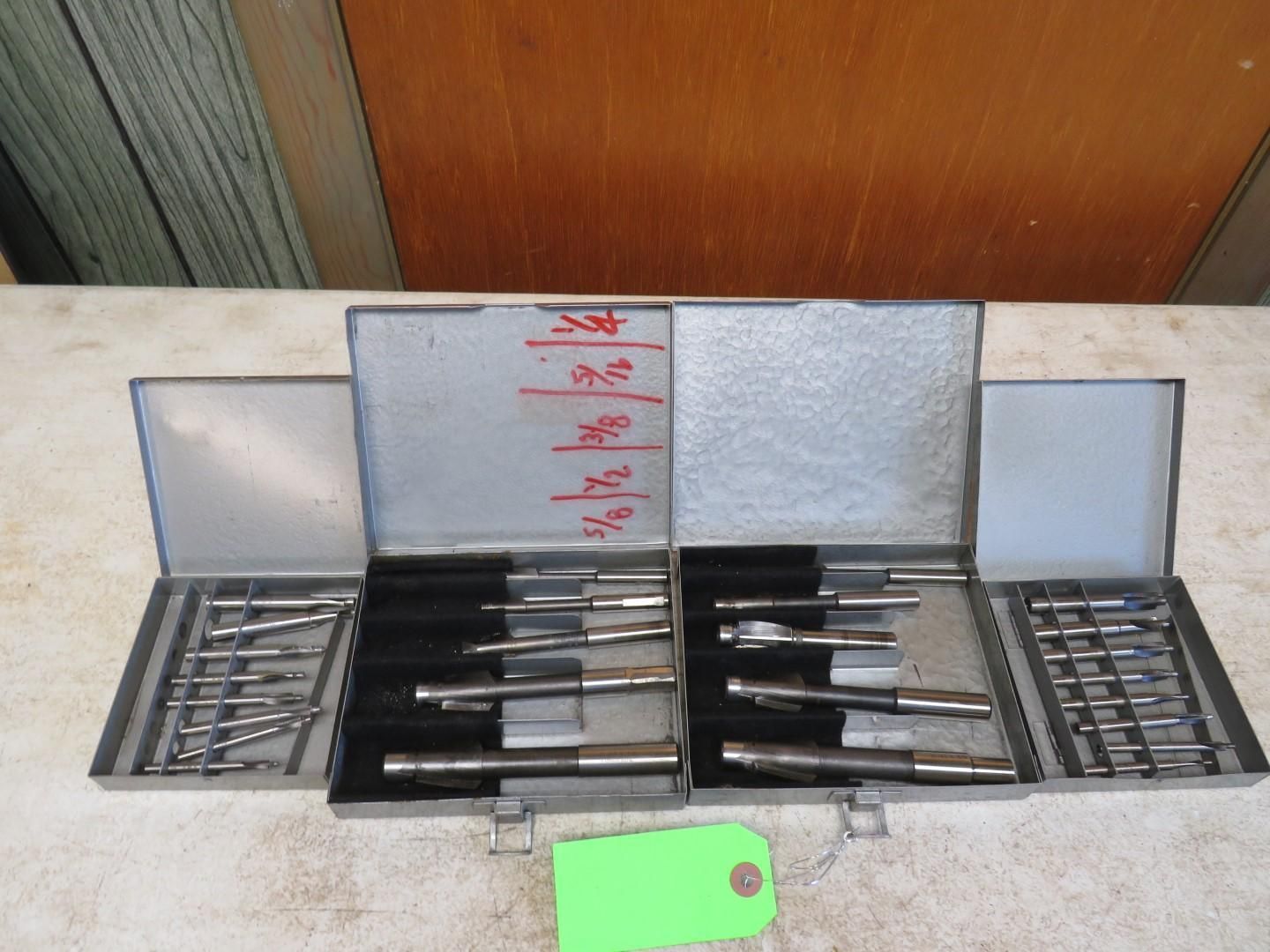 Two open metal toolboxes with various machine shop tools on a workbench.