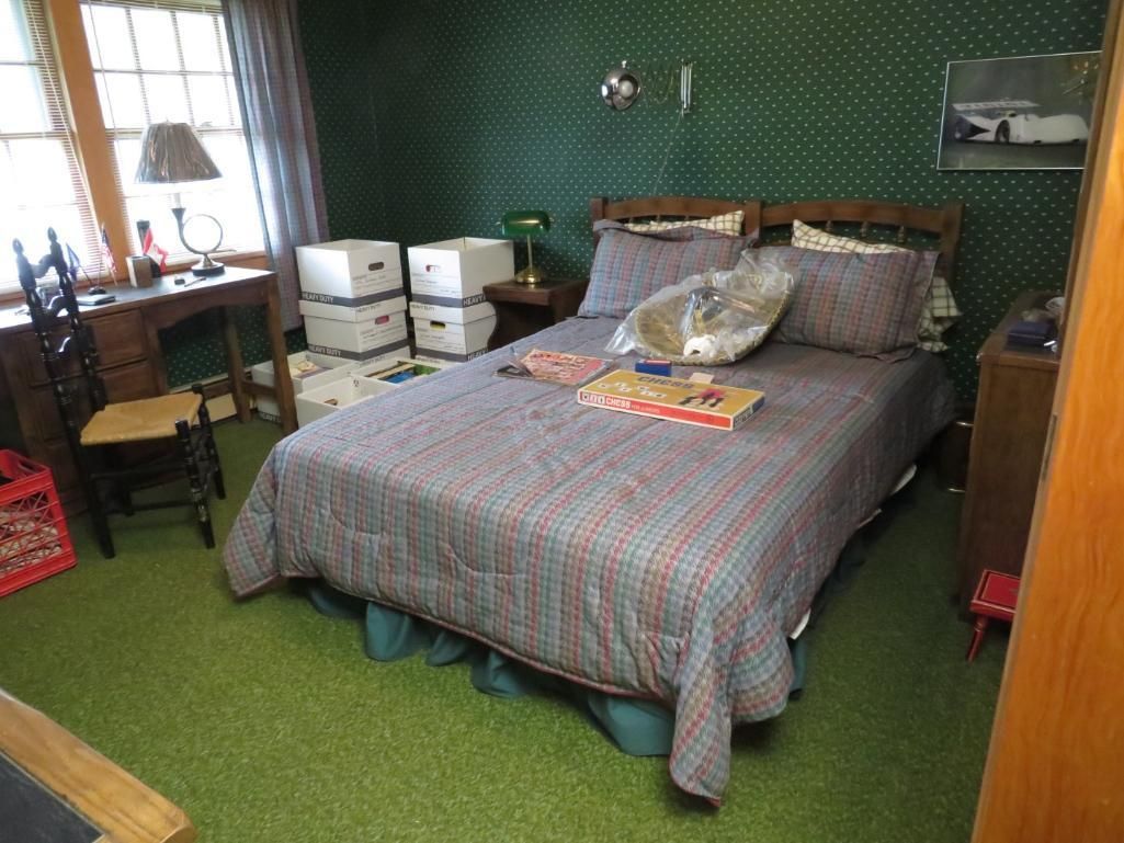 Bedroom with bed, desk with chair, green carpet, and green patterned walls.