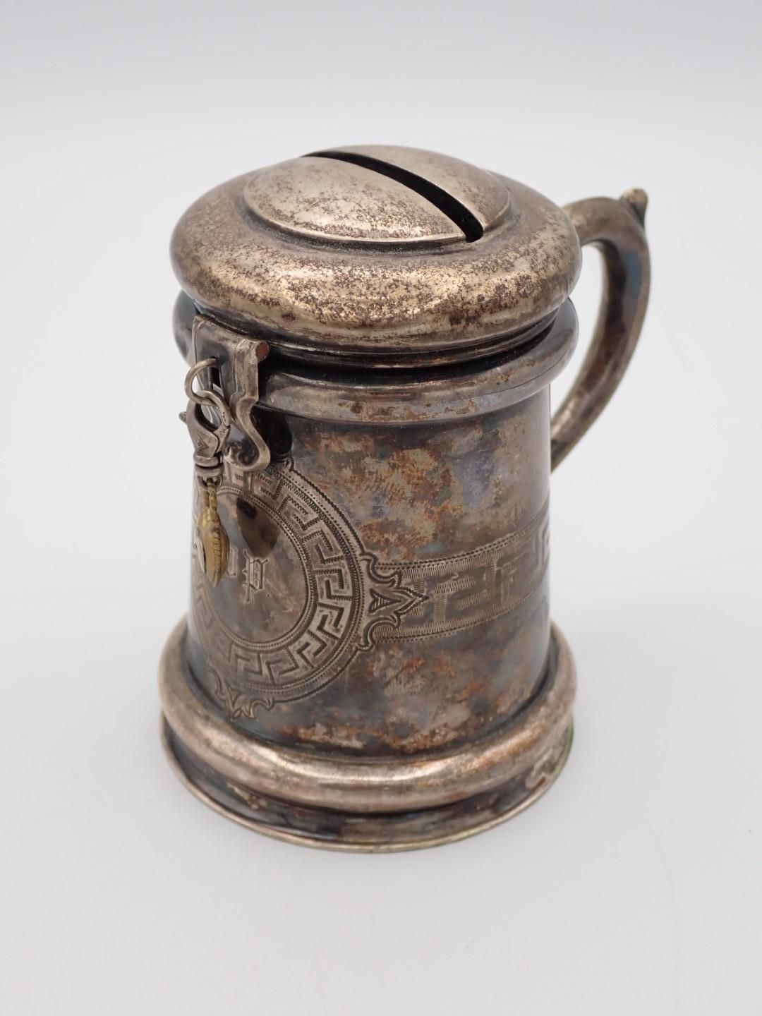 Silver-colored coin bank shaped like a beer mug, with a slot in the lid and decorative detailing.