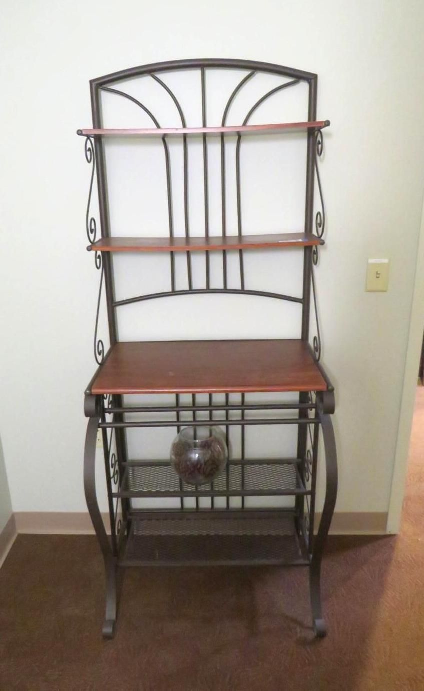 Metal and wood baker's rack with four shelves, a decorative glass globe, and a dark brown floor.