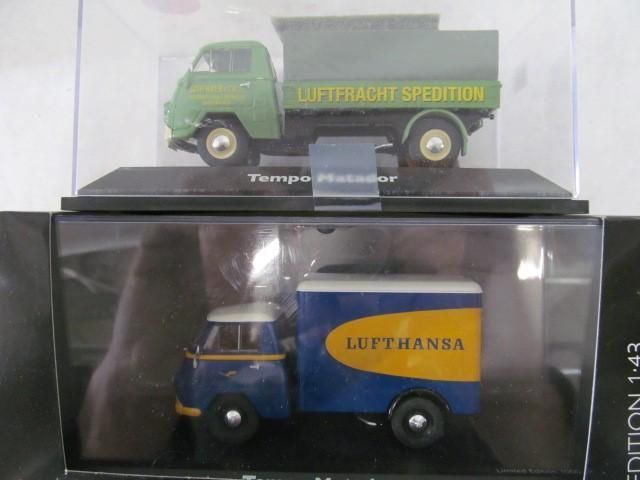 Two Tempo Matador model trucks in clear display cases; one green, the other blue with Lufthansa logo.