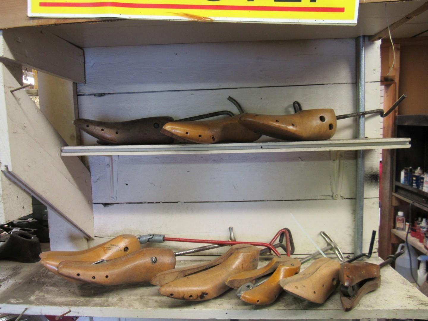 Shoe lasts on shelves in a workshop. Wooden forms, some with metal adjusting rods.