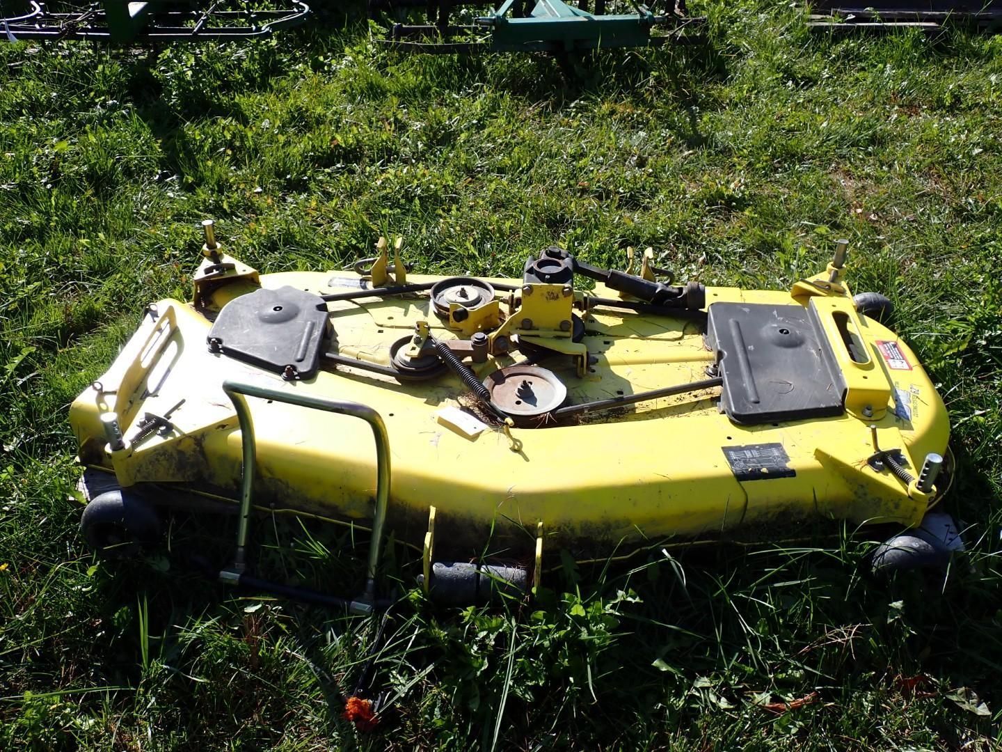 Yellow mower lying in grass, with cables and mounted equipment on top