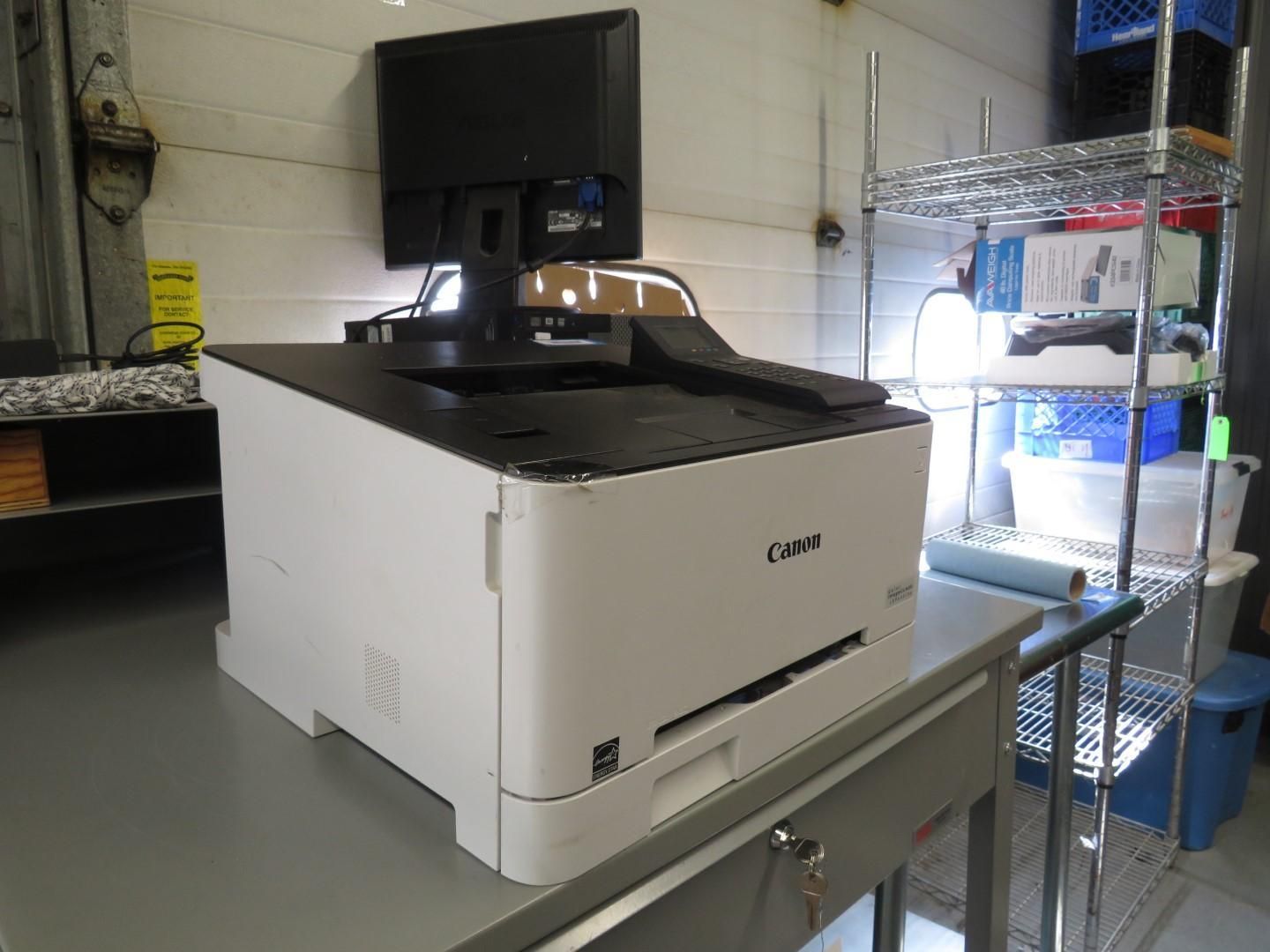 White printer with monitor on top, on a countertop, in a warehouse-like setting.