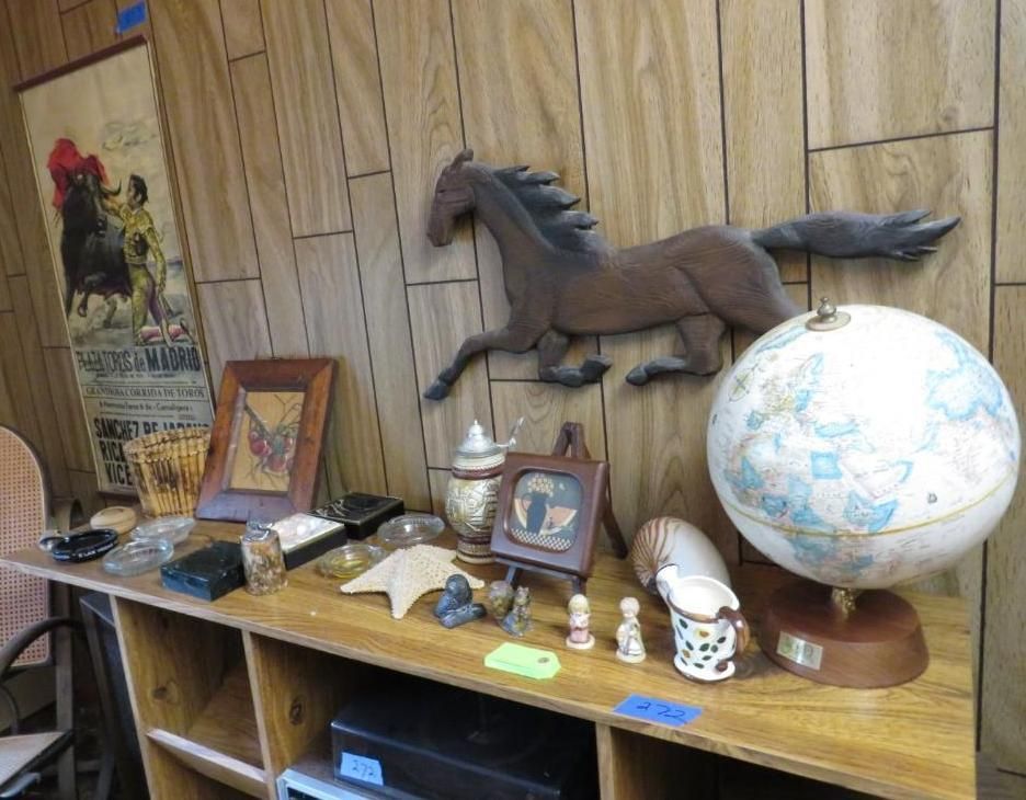 Shelf with various items: horse sculpture, globe, framed artwork, decorative objects. Wooden panel background.