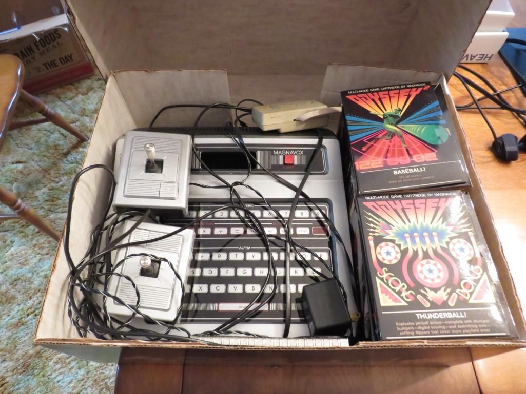 Vintage computer and game cartridges in a cardboard box.