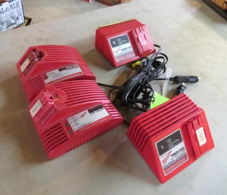 Four red power tool chargers on a light-colored surface. One has a car adapter.