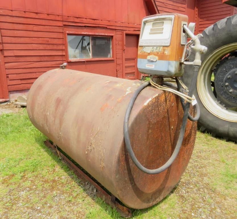Fuel tank with gas pump against a red barn and large tractor tire.