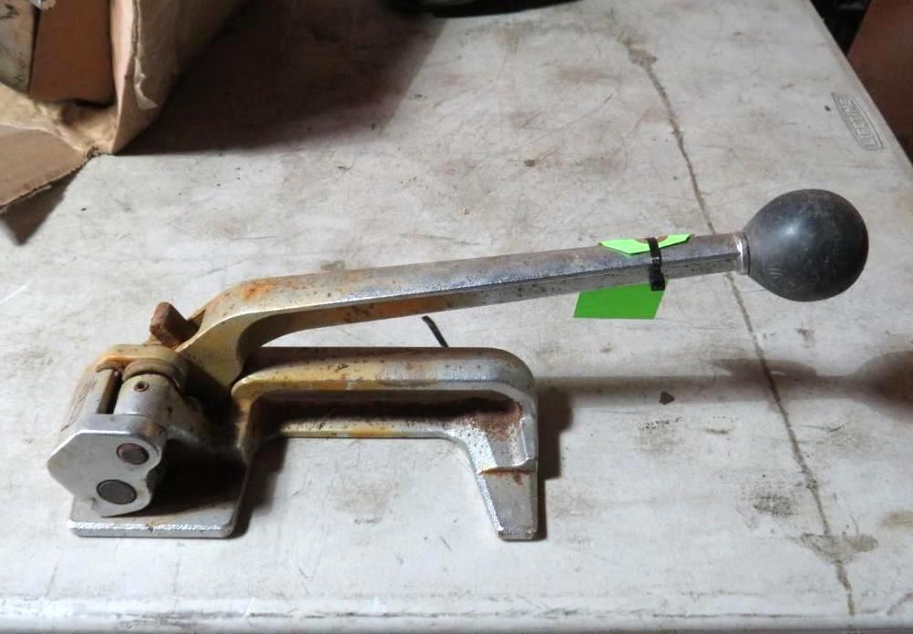 Metal banding tool on a weathered surface, with a black handle and a ball end.