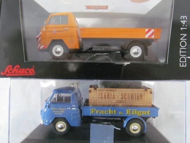 Two model trucks in boxes. One orange, one blue with a wooden crate.