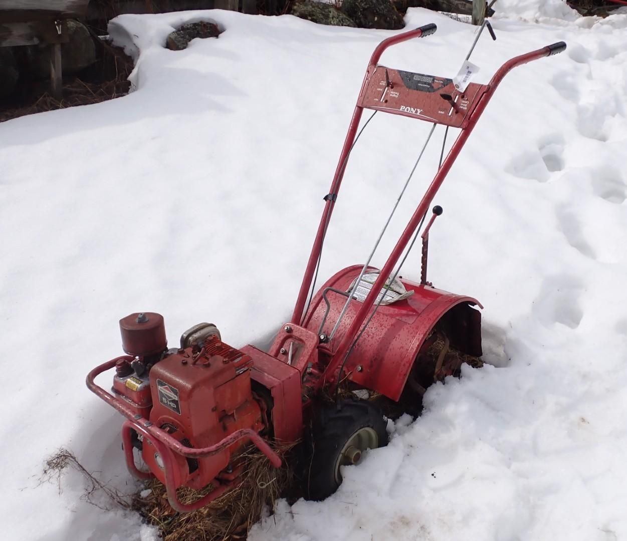 A red rear-tine rototiller.