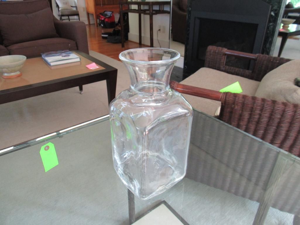 Clear, square glass vase on a glass table.