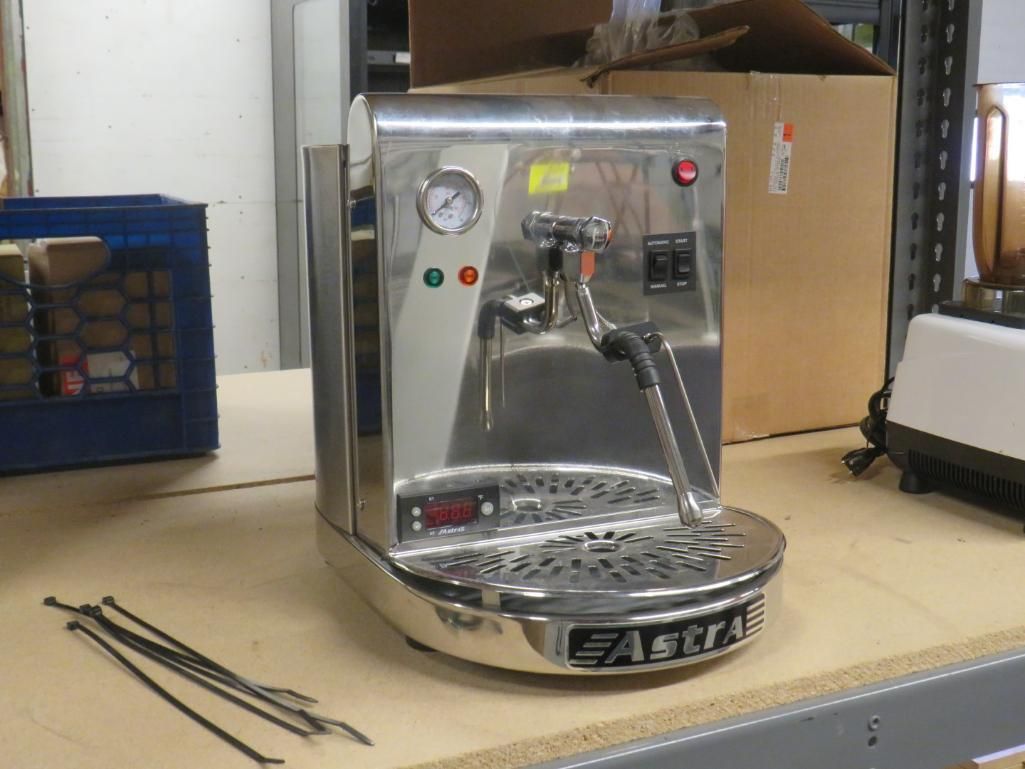 Stainless steel Astra espresso machine on a workbench, with black steam wand and pressure gauge.
