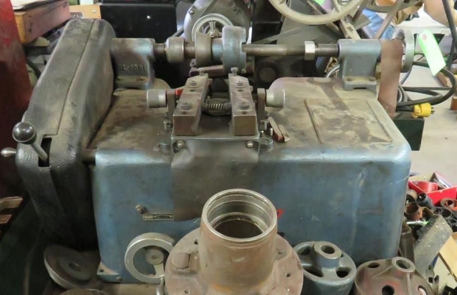 A dusty blue metal machine with various parts, possibly for automotive work, indoors.