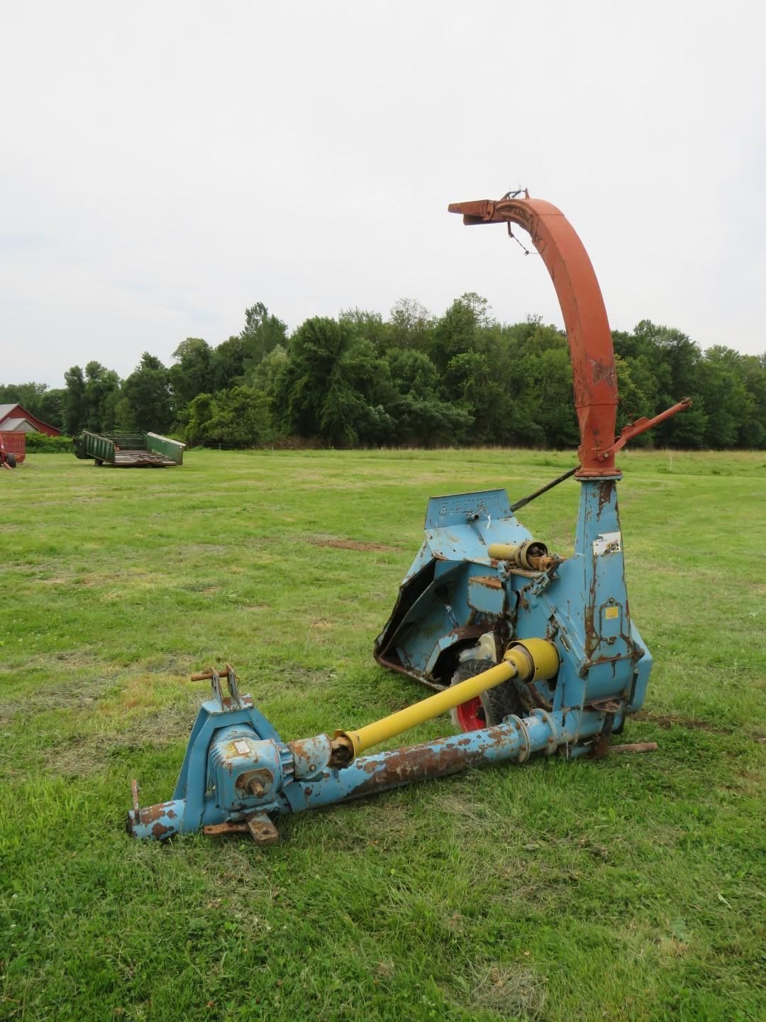 Blue and orange farm forage harvester on a green field.