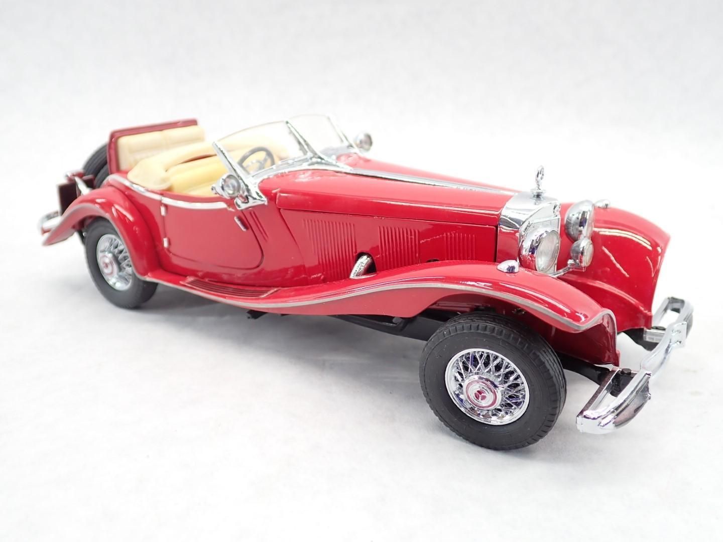 Red classic convertible car with cream interior, chrome details, and spoked wheels.