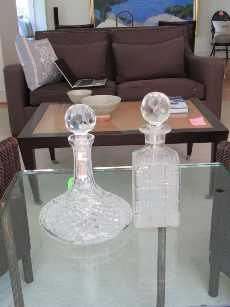 Two glass decanters on a glass table.