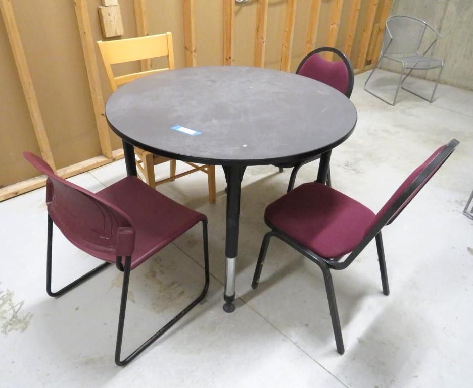 Round table with three burgundy chairs and one yellow chair in a room.