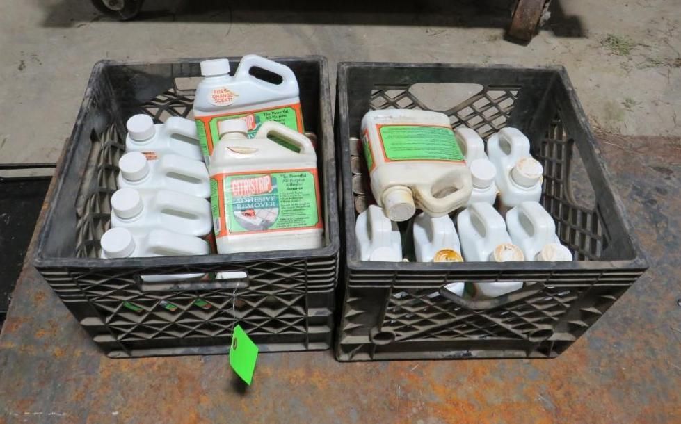 Two black crates filled with white and green chemical bottles.