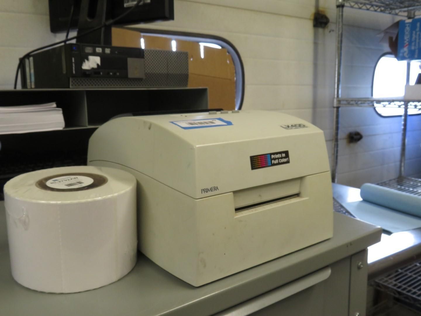 Label printer and roll of labels on a desk, possibly in a work setting.