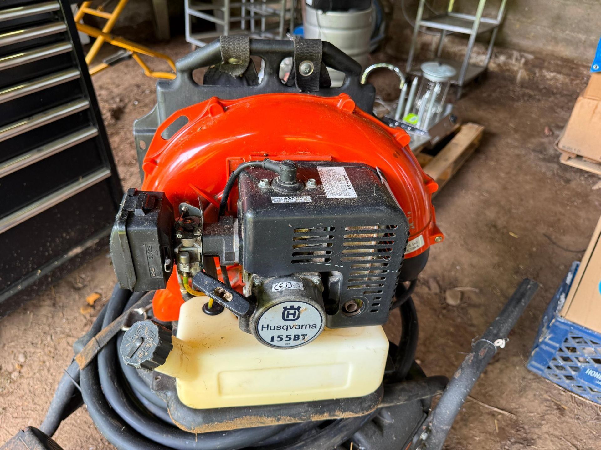 Orange and black Husqvarna backpack leaf blower on a concrete surface.