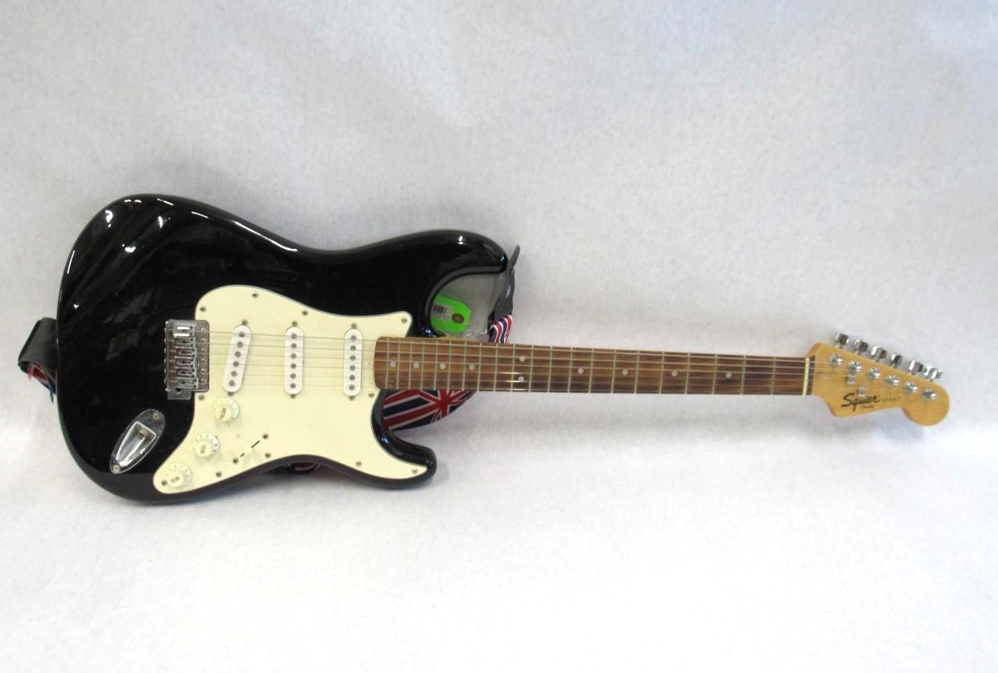 Black electric guitar with white pickguard, maple neck, and headstock with 