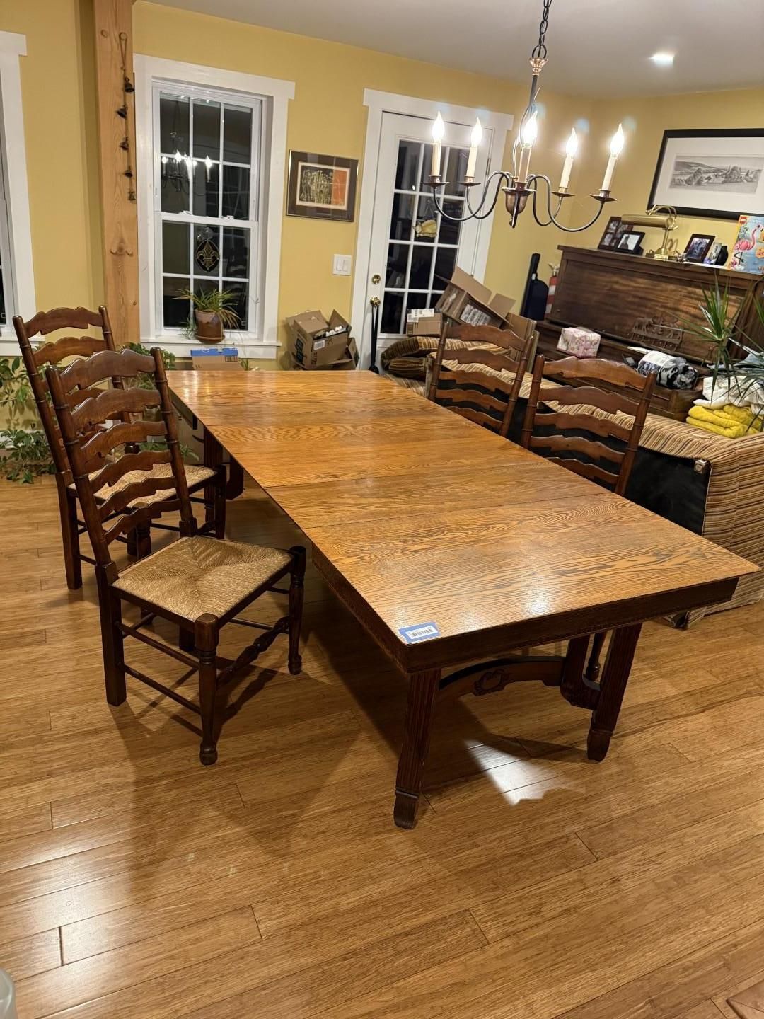 Wooden dining table with six ladder-back chairs and a straw seat in a yellow-walled dining room.