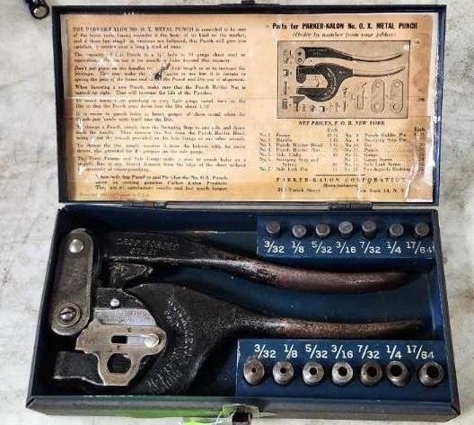 Open metal tool box containing a hand punch, punches, and instructions; vintage style.