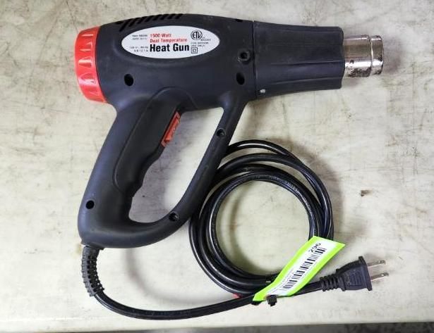 Black heat gun with red nozzle, resting on a white surface. Power cord extends to the right.