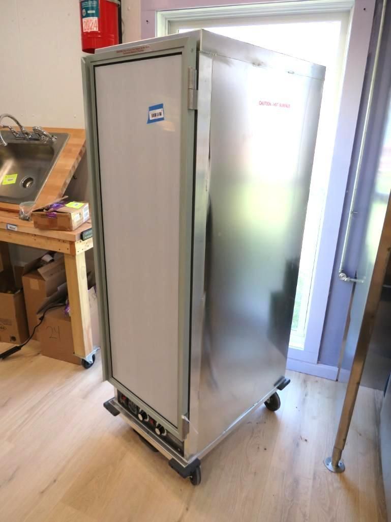 Stainless steel food warmer on wheels in a commercial kitchen setting.