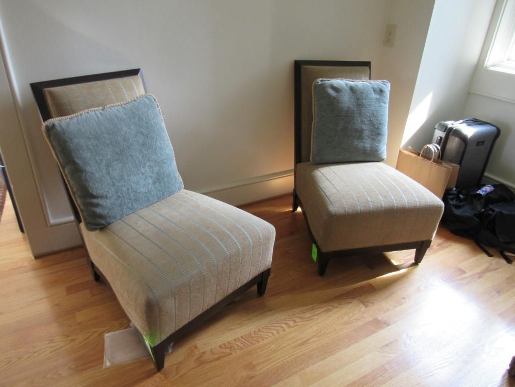 Two upholstered chairs with blue pillows on a light wood floor.