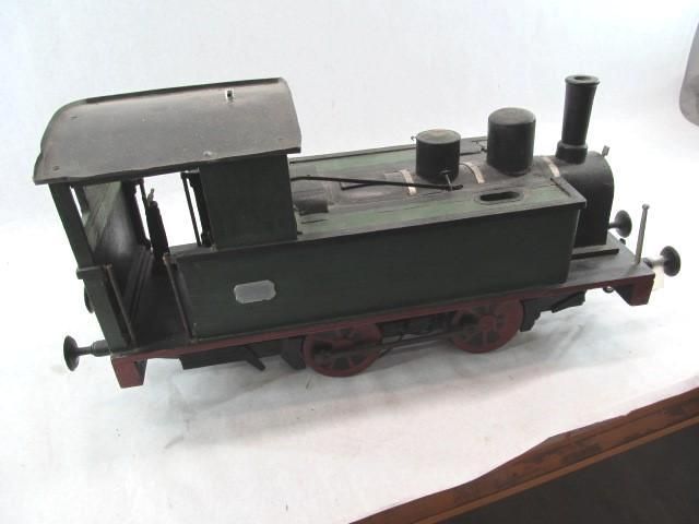 Vintage model train, dark green and black, on tracks.