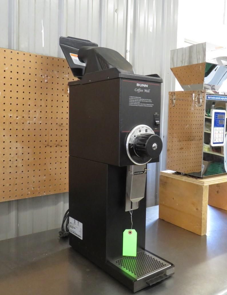 Black coffee grinder on a metal surface, with a green tag hanging from it.