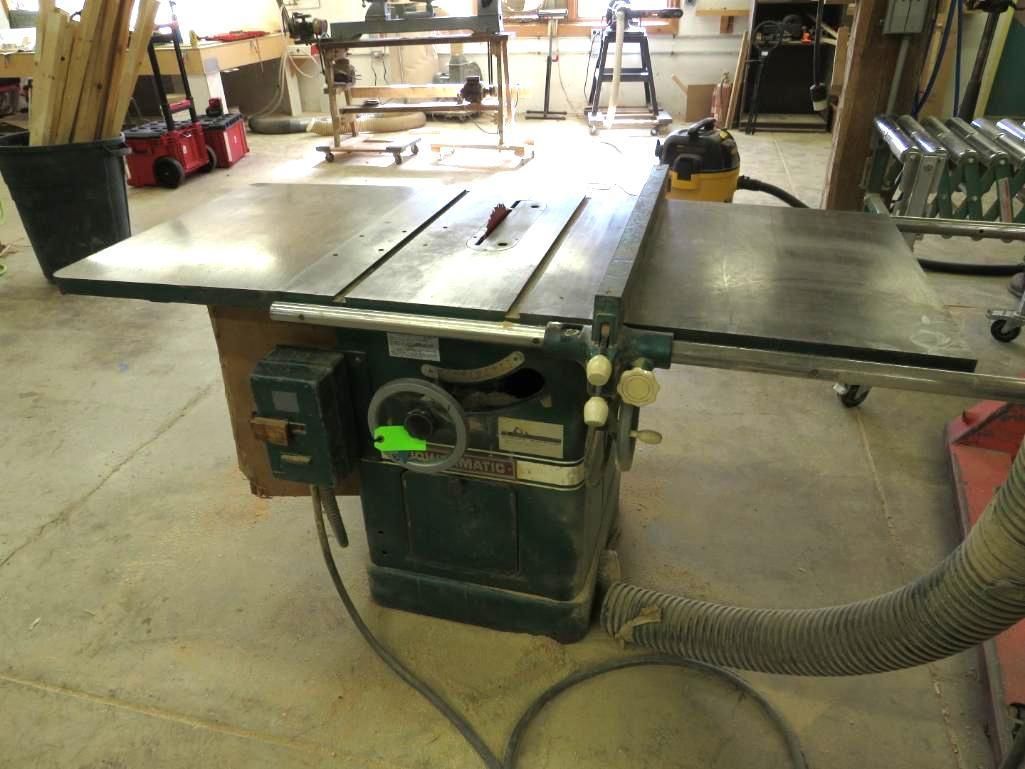 Table saw in a workshop with a wooden table, power cord, and a dust collection hose.