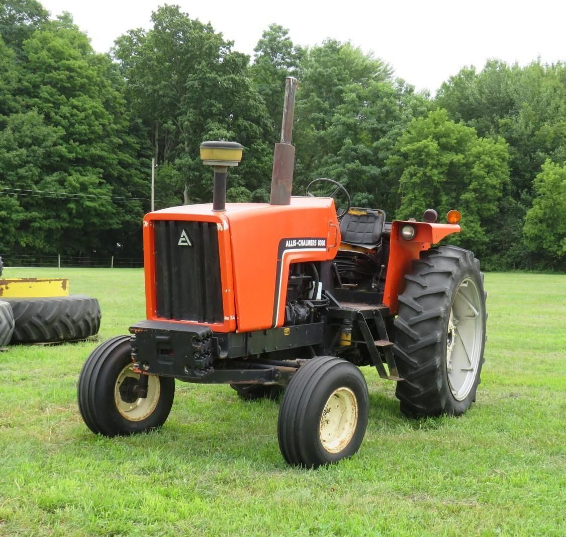 Orange tractor on green grass. Tall exhaust, black grill, and yellow wheels.