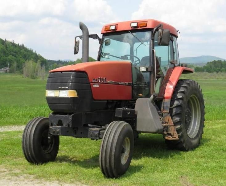 Red Case IH tractor on a grassy field with a mountain backdrop.