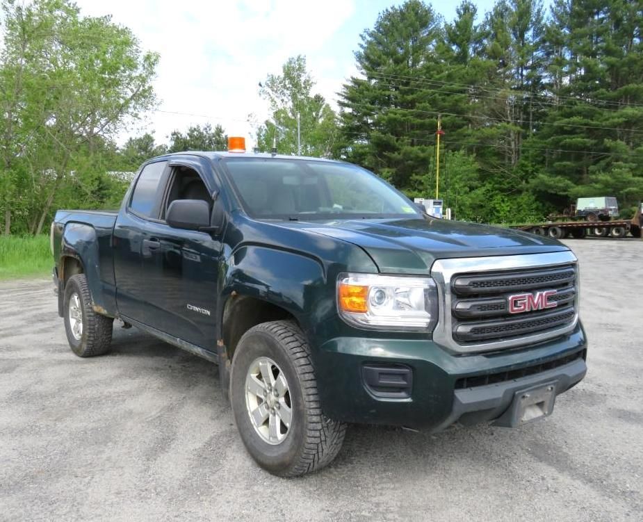 Green GMC Canyon pickup truck parked on gravel.