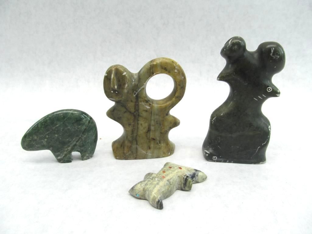 Four small, carved stone animal figurines: a bear, an abstract shape with a hole, a figure with a head, and a turtle.