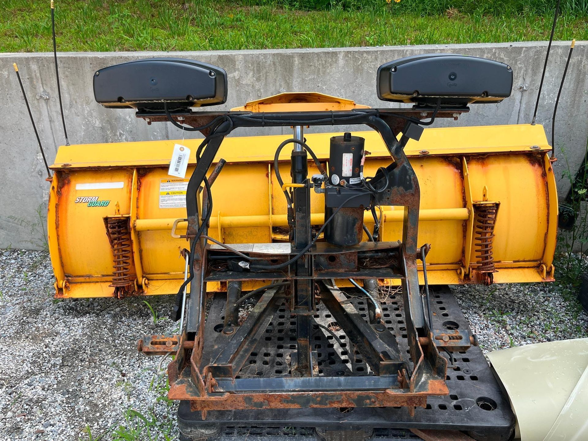 Yellow snowplow with black frame, attached to a vehicle.