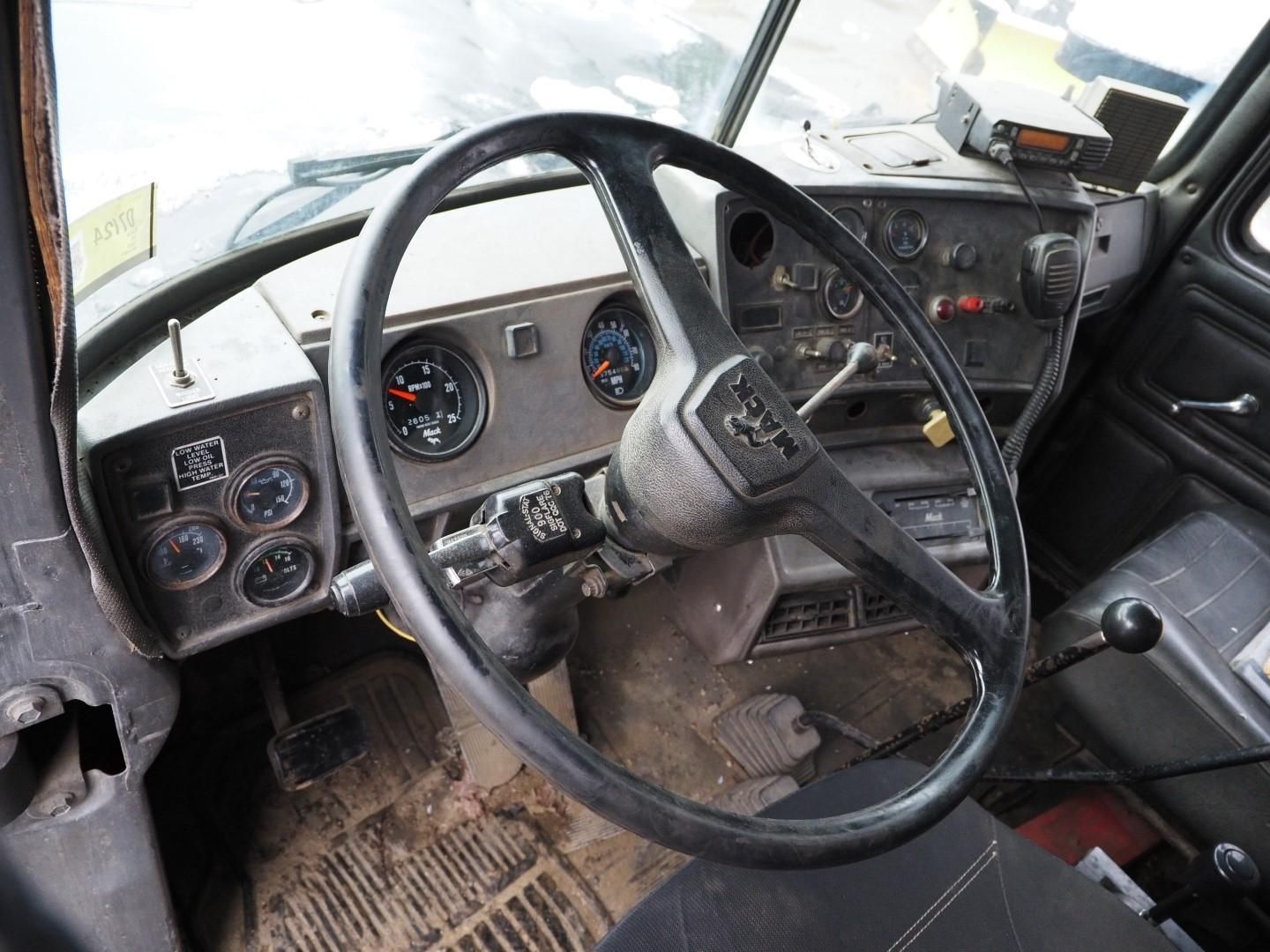 Interior of a truck cab, showing dashboard, steering wheel, gauges, and pedals.