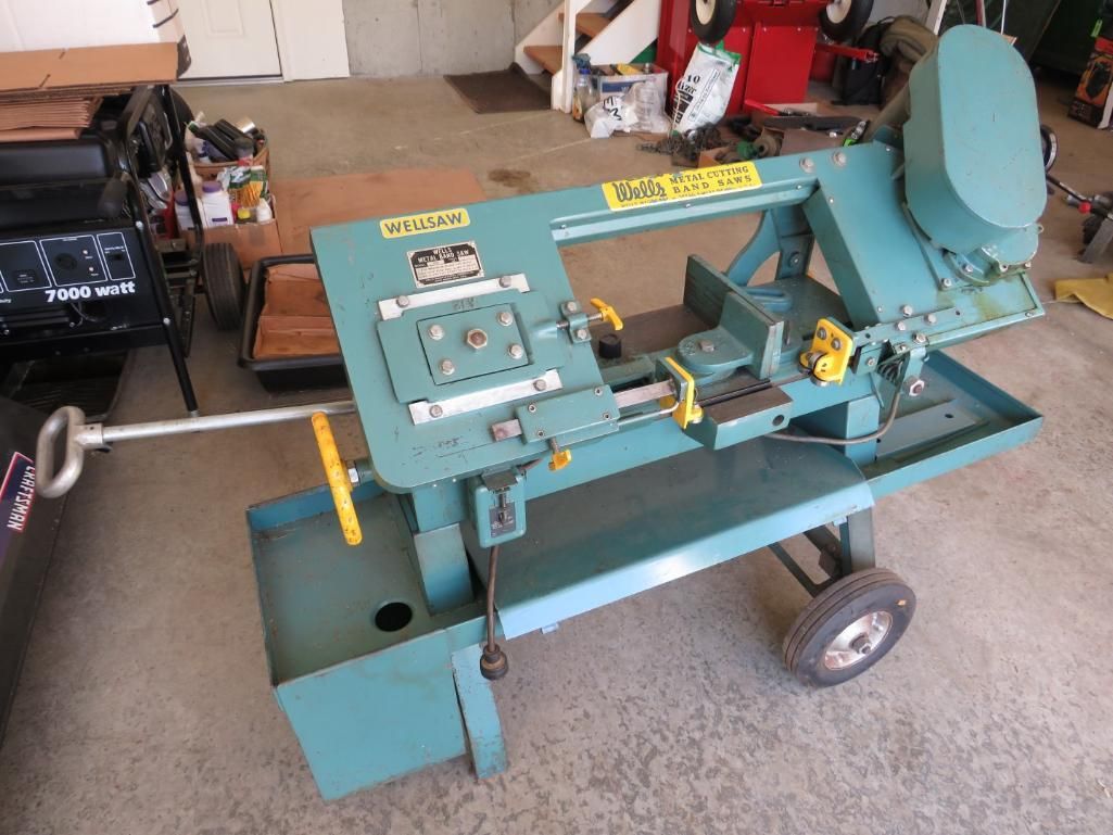 Blue horizontal band saw on wheels, used for cutting metal.