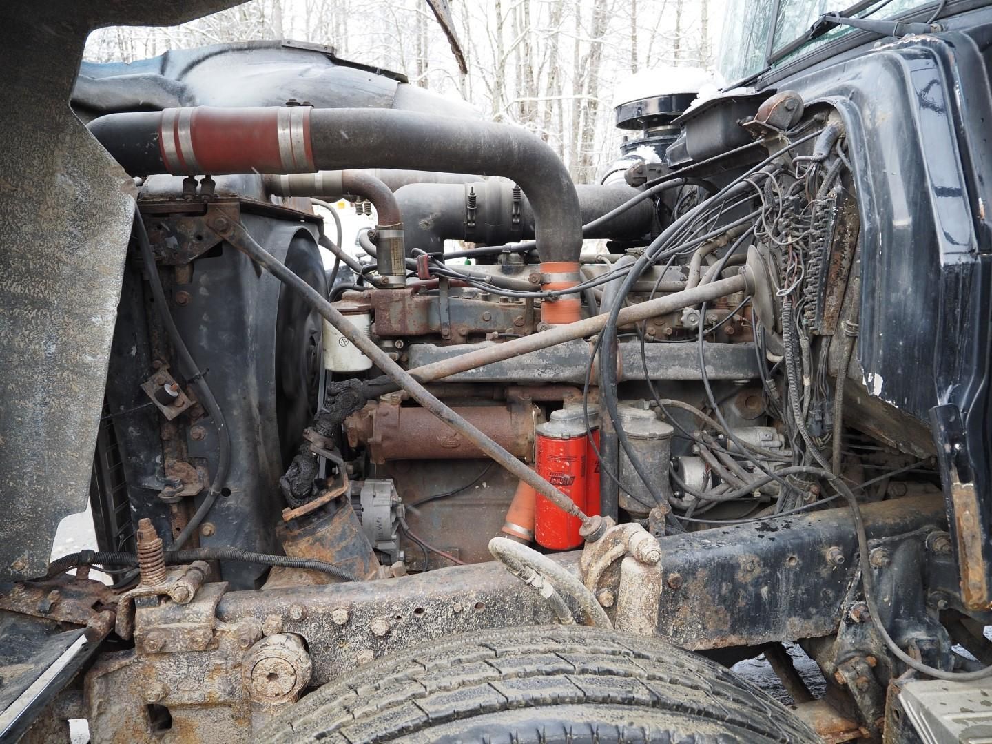 Open truck engine bay with exposed components, including pipes, filters, and various hardware.