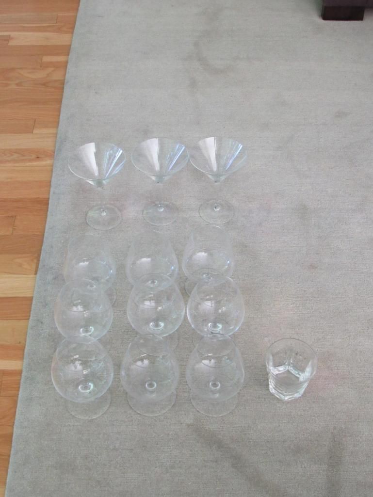 Twelve clear stemmed glasses arranged on a light brown carpet.