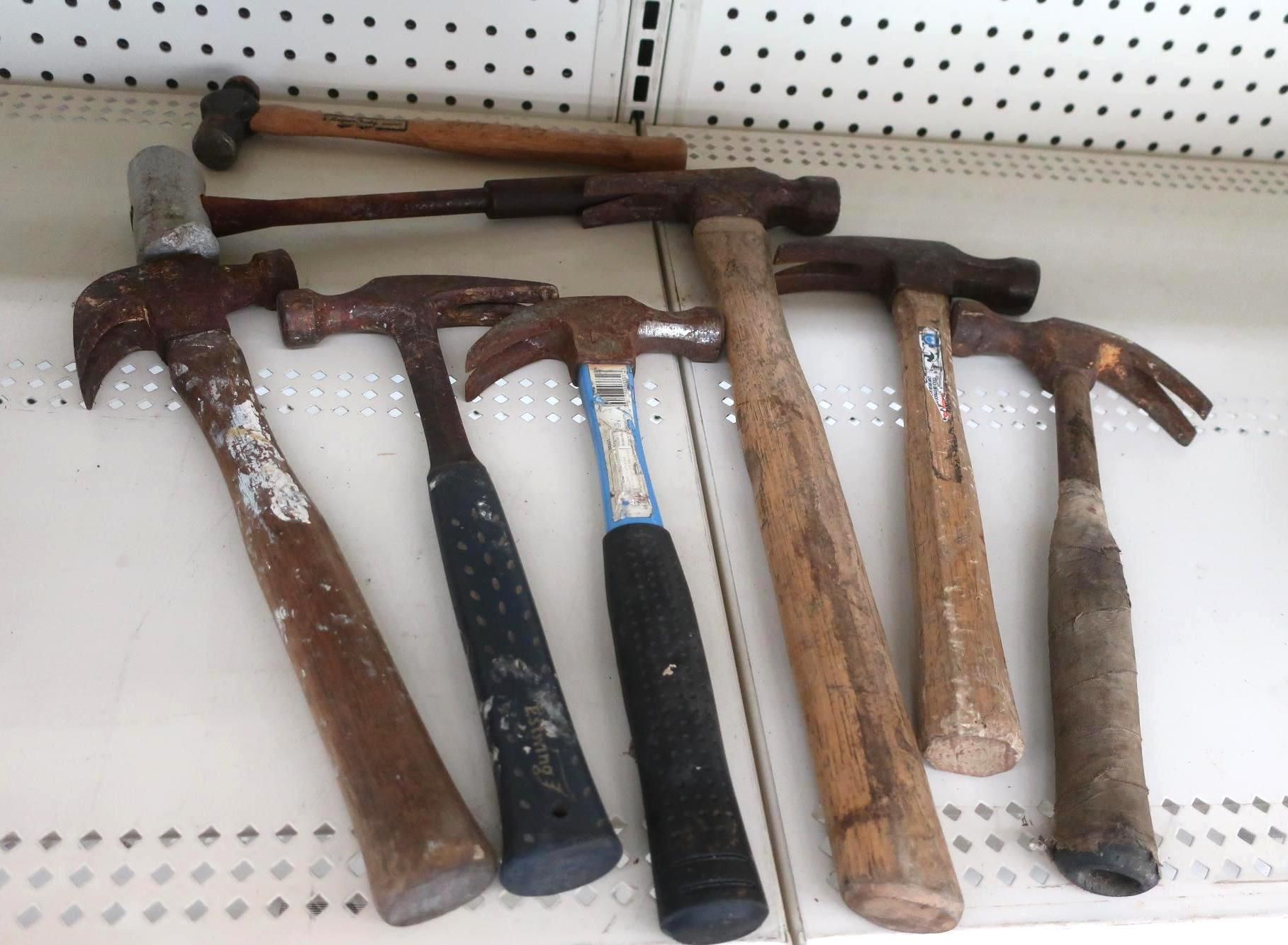 Several hammers of varying sizes arranged on a shelf.