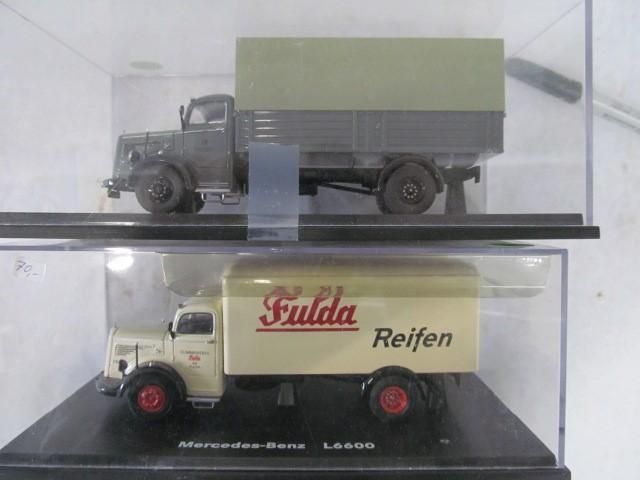 Two model Mercedes-Benz L6600 trucks in display cases. One gray with a canvas top, the other cream, marked