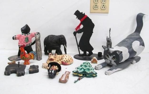 Collection of various carved animal and human figures on a white surface, including an elephant and a cat.