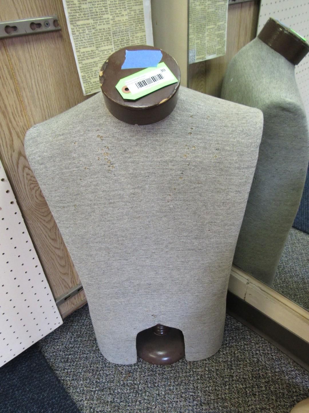 Mannequin torso with brown base, and neck, covered in textured gray fabric.