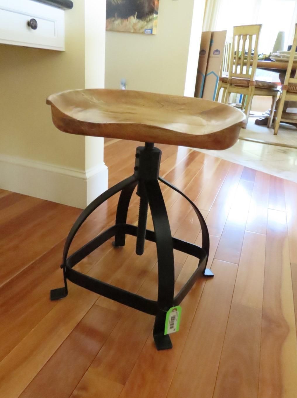 Wooden stool with a carved seat and black metal base.